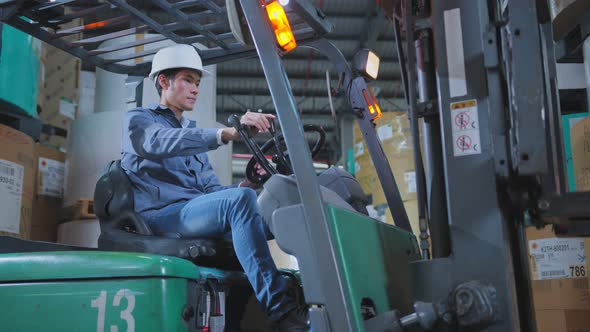 professional asian male engineer control fork lift truck loading product pallet