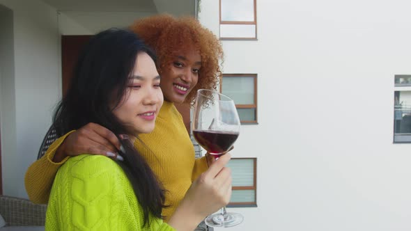 Interracial Couple of Girlfriends Drinking Wine on the Balcony . 