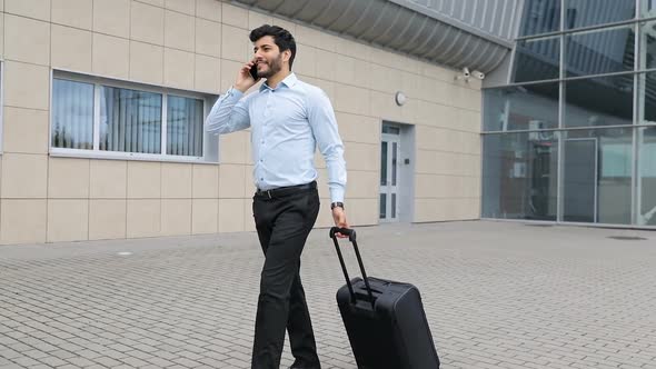 çBusiness Trip. Handsome Man With Phone And Suitcase At Airport