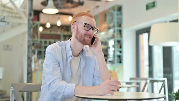 Redhead Man Talking on Smartphone in Cafe 