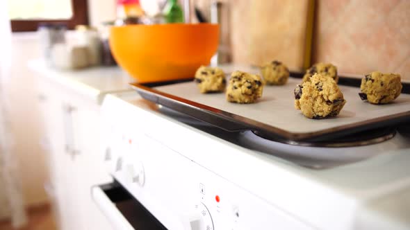 Shaped Balls of American Chocolate Chip Cookies Lie on a Baking Sheet on an Oven