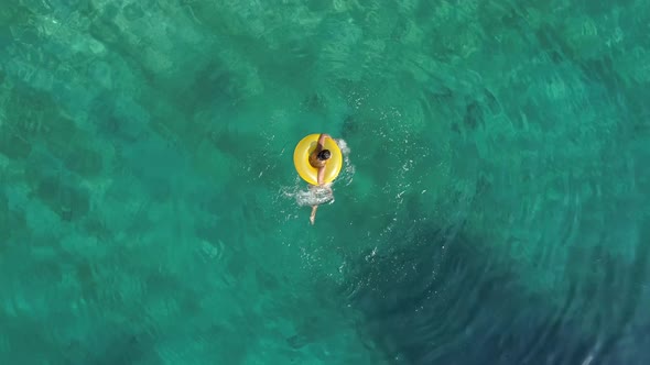 Aerial view of woman spinning with inflatable on Atokos island, Greece.