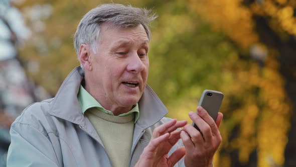 Happy Elderly Smiling Mature Caucasian Male Grandfather Make Remote Video Call By Mobile Smartphone