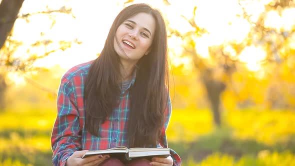 Brunet girl in shirt with notebook at apple tree garden. Spring time