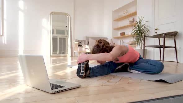 Lady Does Forward Bends According to Video Tutorial on Floor