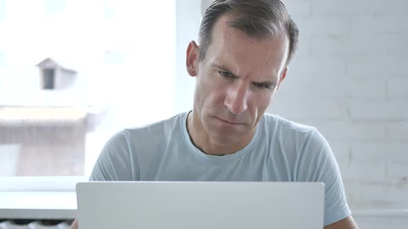 Tired Man Yawning While Working on Laptop