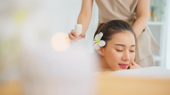 Asian beautiful woman enjoy thai hot compress massage with herbal bags.