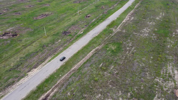 A Lonely Car Drives Along an Empty Road Outside the City in the Countryside