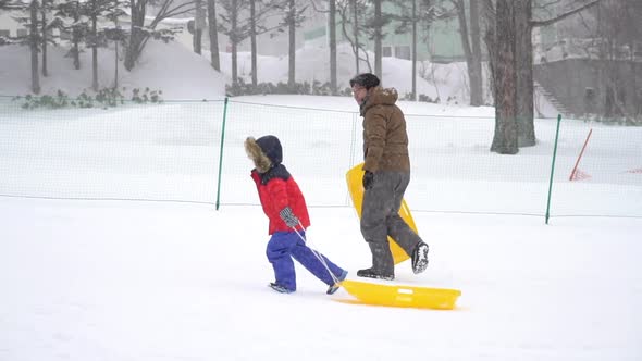 Asian Father And His Son Walking Under Snow Fall