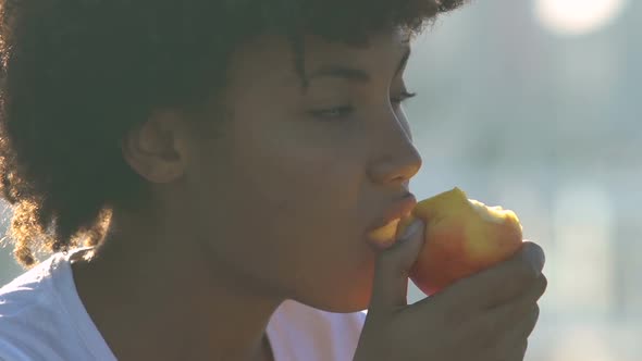 Beautiful African American Woman Eating Apple on City Street, Healthy Snacks