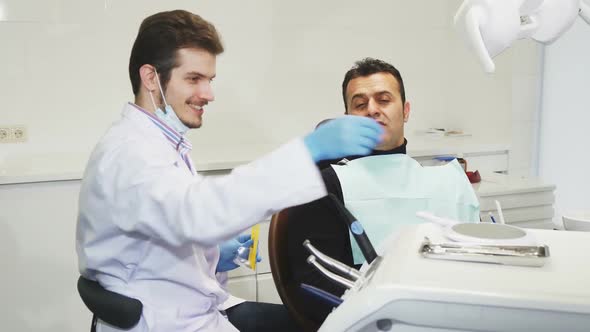 Professional Dentist Giving a Mirror To His Patient After Dental Treatment