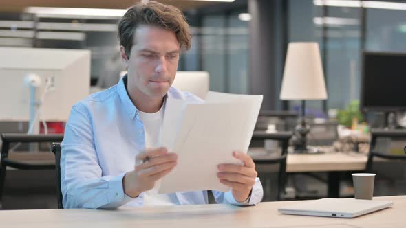 Man Reading Documents While Sitting in Office