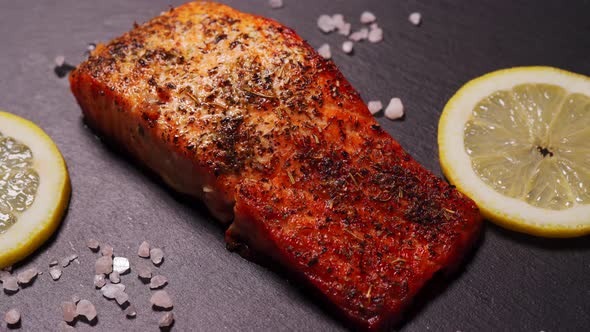 Delicious Baked Golden Salmon on a Black Plate in the Kitchen