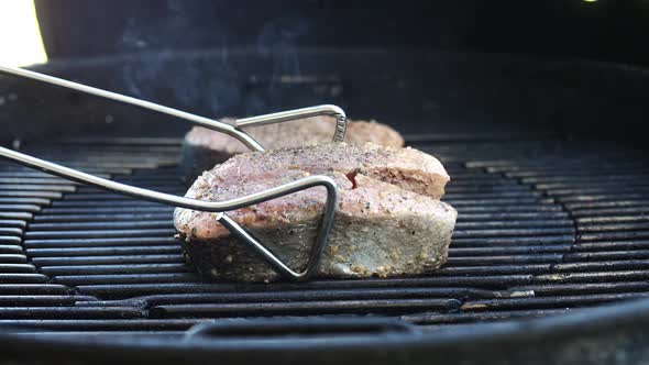 Flipping salmon steaks of the grill to sear the other side - isolated close up