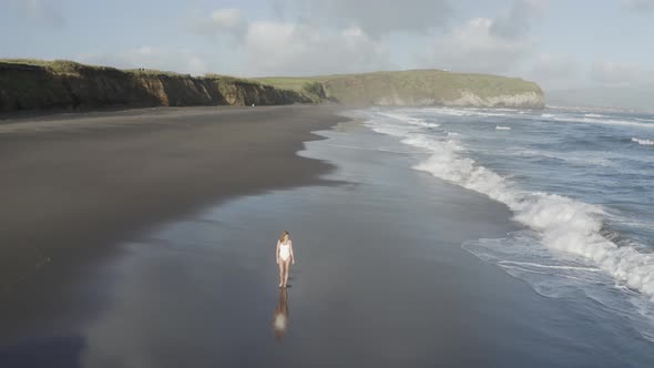 Aerial View of a woman walking on the beach, Praia do Areal, Azores, Portugal.