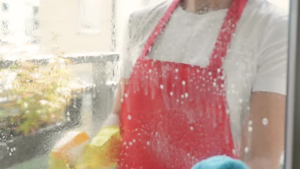 Female Hands in Yellow Gloves Cleaning Window Pane with Rag and Spray Detergent