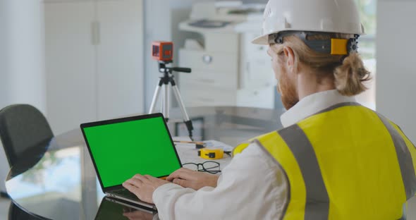 Over Shoulder Shot of Civil Construction Engineer Working with Laptop at Desk in Office