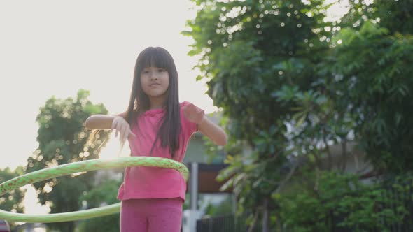 Young Asian little girl playing hulahoop exercise outdoor at home for health care and wellbeing.