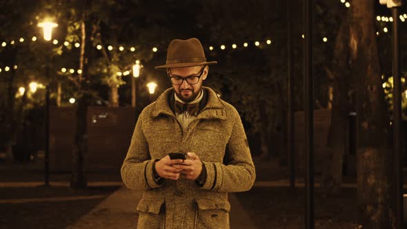 Portrait of Happy Man Reading Sms on Mobile Phone Outdoors