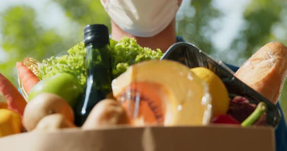 Delivery man wearing face mask giving a grocery bag to the customer,  slow motion close up shot