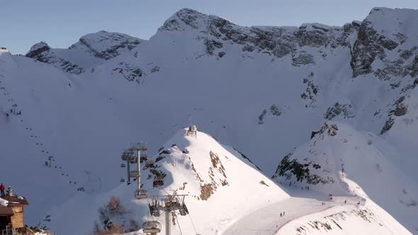 Ski lift moving with skiers on snow mountain resort aerial view