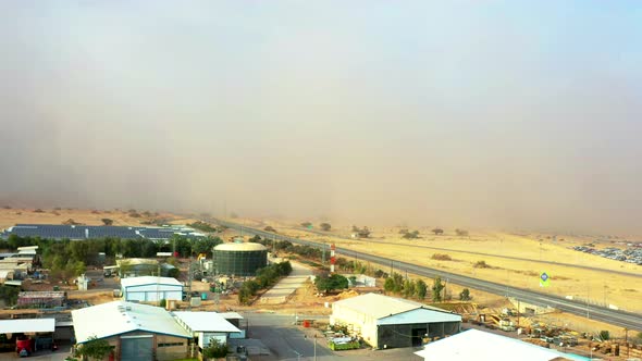 Large sandstorm sweeps across the dry yellow landscape of Israel's Southen Arava as a car pulls out