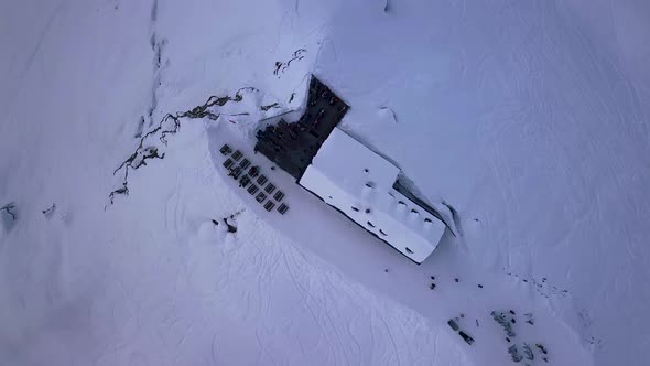 Aerial drone shot rising up over a ski lodge and the snowy slopes above the vacation resort town of