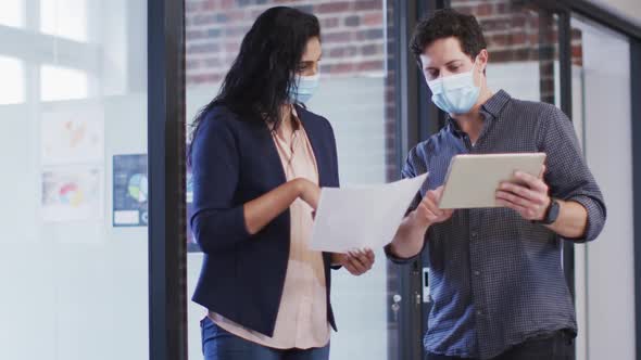 Man and woman wearing face masks discussing at office