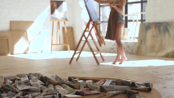 Girl Paints Picture of Oil Standing Barefoot on Floor Studio