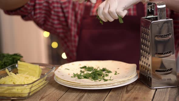 Closeup View of Man Hands in Protective Gloves Who Rips Fresh Parsley and Sifts It on Tortilla
