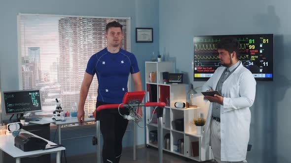 Multiracial Sport Professional Performing Stress Test While the Athlete Walking on Treadmill