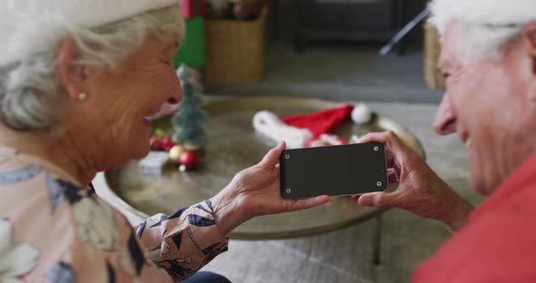 Caucasian senior couple in santa hats on video call on smartphone with copy space at christmas time