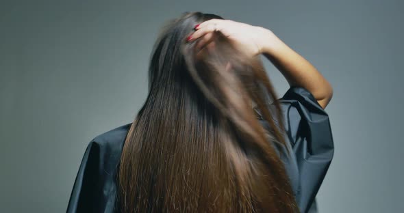 Back View of Brunette Woman Playing with Her Hair Over Clear Background