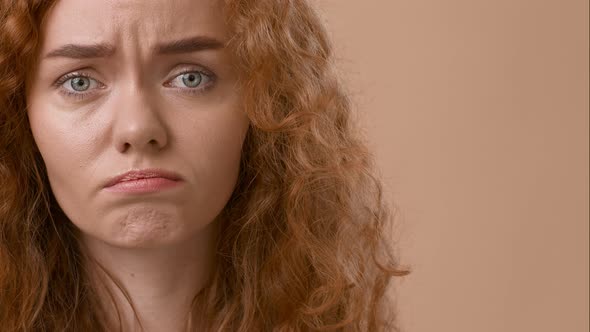 Sad RedHaired Woman Looking At Camera Expressing Frustration Beige Background