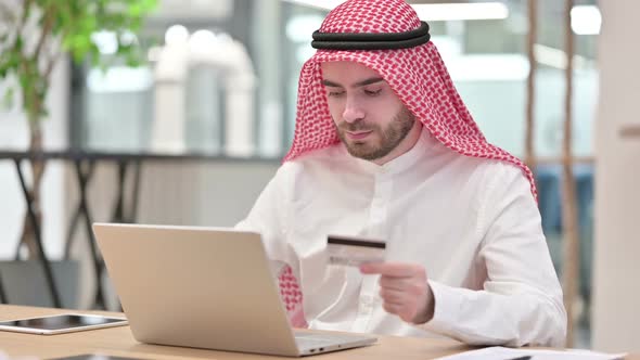 Online Payment Success on Laptop for Arab Businessman in Office