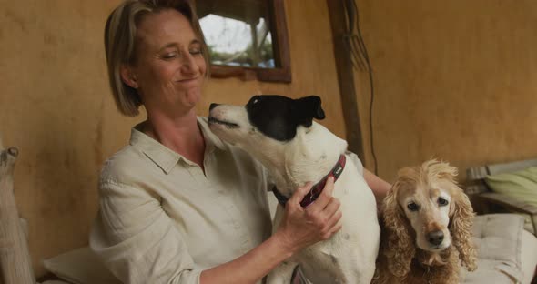 Smiling senior caucasian woman playing with her two dogs at home