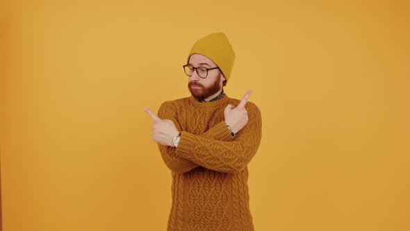 Young Caucasian Man Hesitating Pointing Sideways with Arms Crossed Orange Background Medium Shot