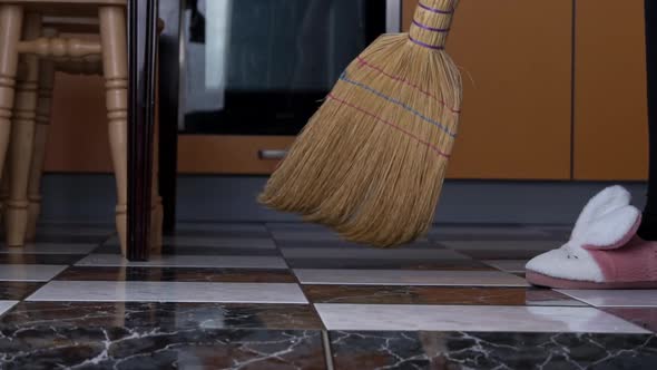 Young Girl Sweeps the Floor in the Kitchen with an Ordinary Broom in Slow Mo