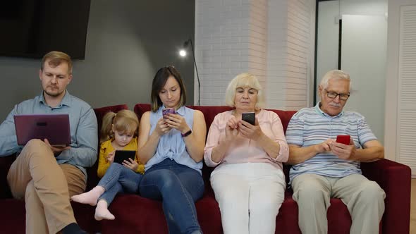 Addicted To Gadgets Family Using Mobile Phone, Tablet, Laptop Ignoring Each Other at Home. Obsession