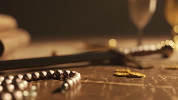 The vintage compass on the ancient map next to the sword, goblets and jewels.