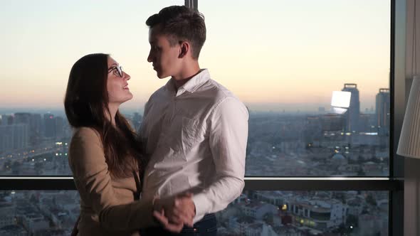 Couple, Man and Woman Are Dancing Near the Panoramic Window with City View