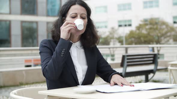 Businesswoman Reading Papers and Drinking Coffee