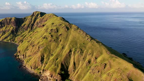 South Padar island east of Komodo Indonesia with grass covered peninsula, Aerial pan right reveal sh