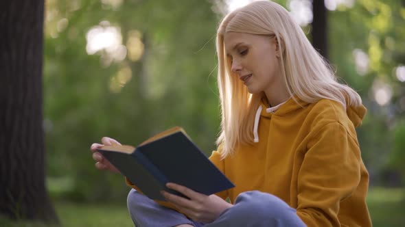 Young Pretty Woman Reads an Adventure Novel with Interest in Nature