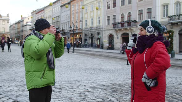 Senior Couple Tourists Grandmother Grandfather Taking Photo Pictures on Retro Camera in Winter City