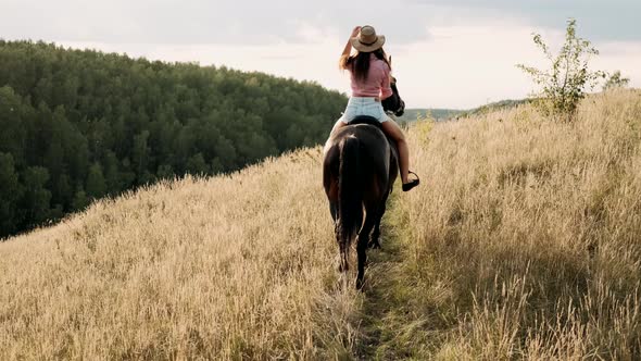 Beautiful Girl Riding a Horse in Countryside. Female Rider Rides a Graceful Horse. Horseback Riding