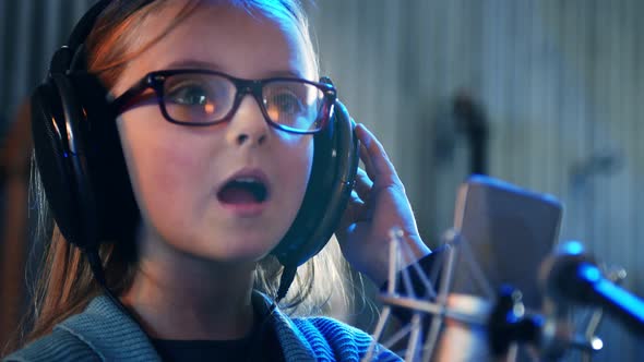 Kid Singing in studio.Little Girl Singing a song.Front View Close Up. Kid Wearing Headphones