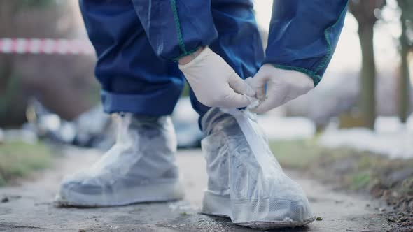 Closeup Unrecognizable Criminologist Tying Shoelaces on Protective Shoes Outdoors