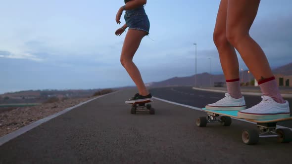 Two Girls Skateboarder Rides on a Board on the Slope Against the Sky From the Mountain. Slow Motion