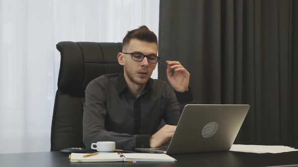 Male employee  tired after busy working day at office sleeping on the desk and rubbing his eyes